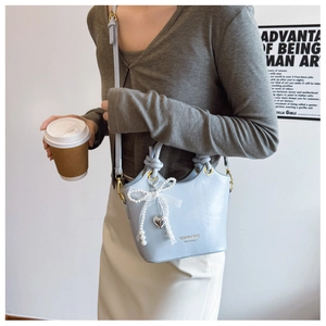 Detailansicht der hellblauen Eimertasche mit Perlenspitze und Knotengriff an einem Model