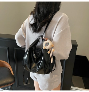 Dettaglio della borsa tote in pelle nera lucida che mostra il drappeggio e il ciondolo