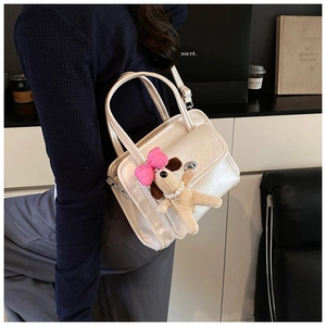 Chic beige leather handbag with cute plush charm and metallic clasp shown on a model