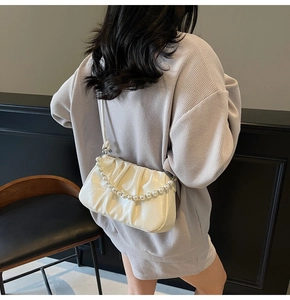 Detail showing creamy white pleated cloud bag with elegant pearl strap and glossy texture