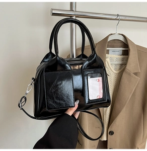 Glossy black patent leather pillow bag with top handles and transparent card slot detail