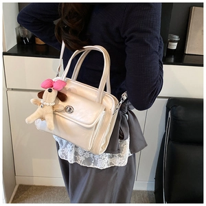 Chic cream leather handbag with plush puppy charm and metal lock detail on模特