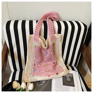 Close-up of pink and cream crochet tote bag with colorful beads on a modern chair