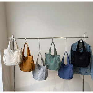 Row of colorful nylon tote bags featuring drawstring pockets and wide shoulder straps