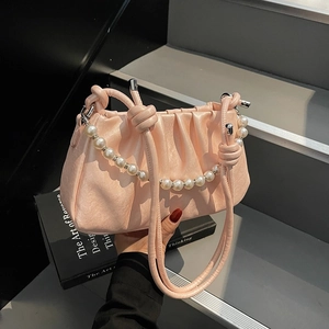 Detailed view of light pink pleated cloud bag with faux pearl chain and knot straps