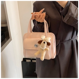 Close-up of pink glossy leather handbag with silver turn-lock and cute puppy charm