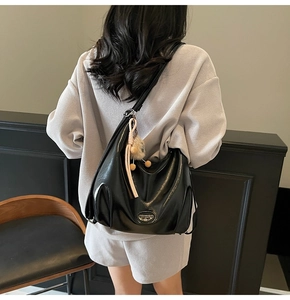 Dettaglio della borsa tote in pelle lucida nera con nappa indossata dalla modella
