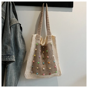 Close-up of crochet hollow mesh tote bag featuring colorful bead accents and wide shoulder strap