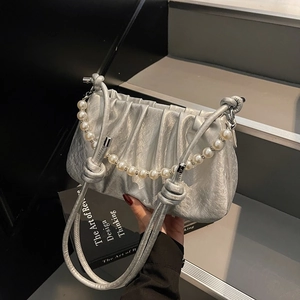 Detail of silver pleated cloud bag featuring glossy finish and elegant pearl chain handle
