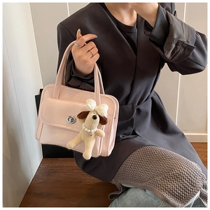 Detail of light pink handbag featuring a silver twist lock and a cute plush dog charm