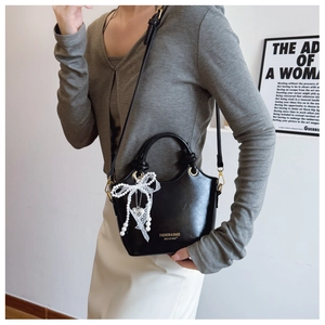 Detailansicht der schwarzen PU-Eimertasche mit Spitzen-Perlen-Anhänger am Model