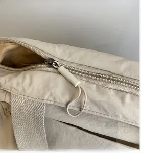 Detail of smooth metal zipper and long pull tab on beige canvas tote bag surface