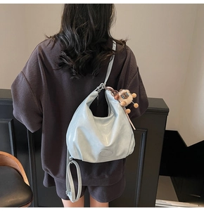 Dettaglio della borsa hobo azzurra con ciondolo a pecora e logo ovale in pelle PU