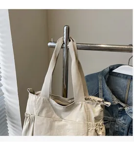 Detail of beige nylon tote bag with side pockets and sturdy handle on a display rack