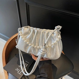 Detailed view of metallic silver pleated cloud bag with large pearl decorative handle