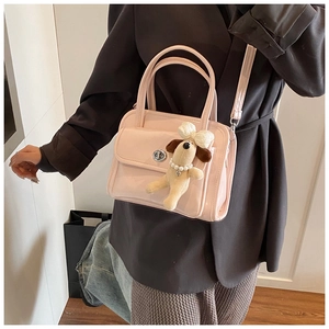 Detail of pink glossy handbag featuring silver twist lock and cute plush dog charm