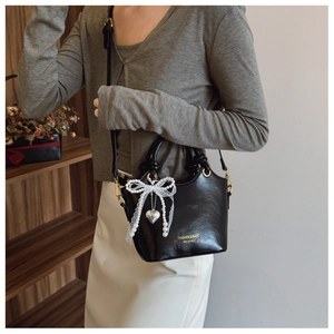 Detailaufnahme der schwarzen Leder-Beuteltasche mit Golddekor und Spitzen-Anhänger
