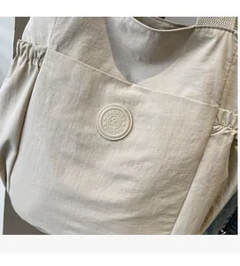 Detail of light beige tote bag featuring fashion circular logo and drawstring pocket