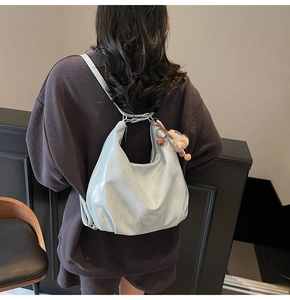 Dettaglio zaino hobo azzurro con ciondolo a pompon marrone e trama in pelle liscia