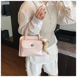 Detail of light pink patent leather handbag featuring a silver oval twist lock and plush puppy charm