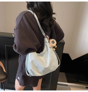 Vista dettagliata di una grande borsa tote azzurra lucida indossata da una modella di spalle