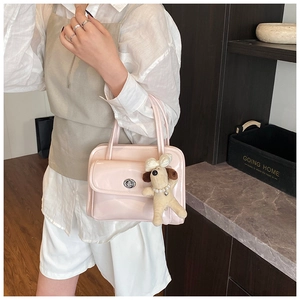 Detail of pink patent leather handbag with silver turn-lock and plush poodle charm