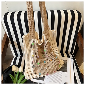 Detailed view of beige crochet tote bag with colorful pearls on a striped armchair