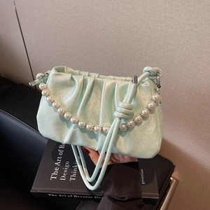 Detail of mint green pleated cloud bag with elegant pearl handle and leather strap