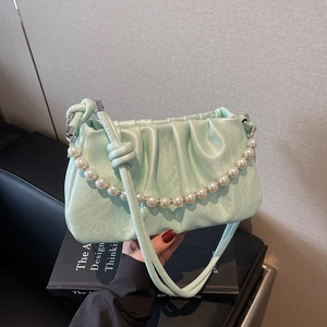 Detail showing mint green pleated cloud bag with elegant pearl handle and leather strap