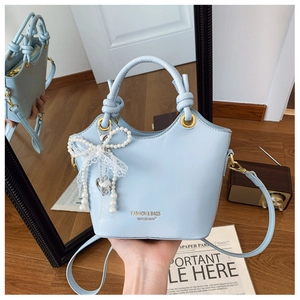 Detail einer hellblauen Handtasche aus Leder mit Perlen-Schleife und gedrehtem Griff Design