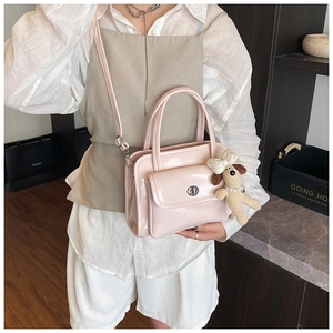 Detail of pink patent leather handbag with metal turn-lock and cute puppy charm