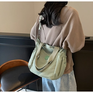 Detail of light green canvas tote bag featuring adjustable strap and side drawstring design