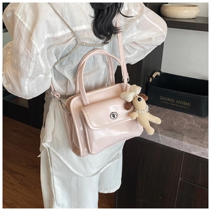 Detail of light pink patent leather handbag featuring silver metal twist lock and dog charm