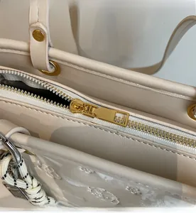 Dettaglio della cerniera in metallo dorato e trama goffrata sulla borsa a secchiello