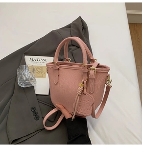 Detail of pink lychee leather texture on mini bucket bag with a cute bear charm accessory