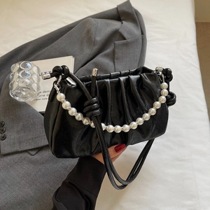 Detail of black ruched cloud bag featuring glossy leather and a large pearl chain strap