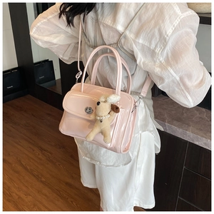 Detailed shot of pink glossy PU leather handbag with silver lock and plush dog charm