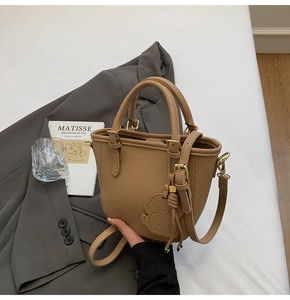 Detail of tan lychee grain leather bucket bag with cute dog charm and gold hardware