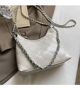 Details der weißen gesteppten Tasche mit Silberkette auf einem Blazer-Hintergrund
