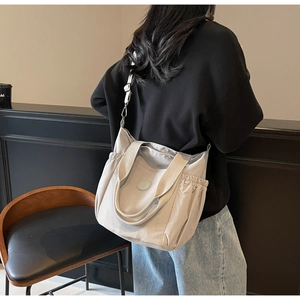 Rear view of model wearing a light grey large capacity tote bag with wide shoulder strap