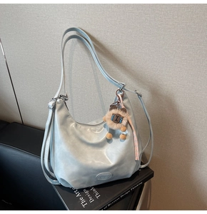Dettaglio della borsa hobo azzurra con tracolla regolabile e ciondolo a leone in peluche