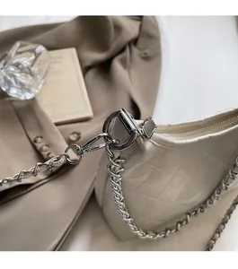 Nahaufnahme der beigen gesteppten Ledertasche mit glänzendem Finish und Silberkette