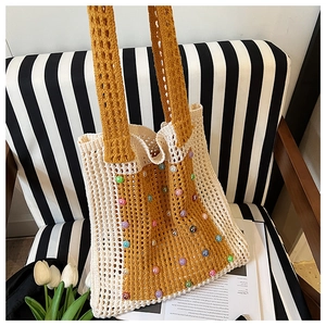 Close-up of handmade knit tote bag with colorful beads and yellow-white contrast design