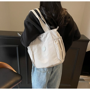 Close-up of light gray multi-pocket tote bag showing spacious capacity and shoulder strap