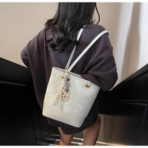 Dettaglio della borsa a secchiello bianca con motivi floreali a rilievo e tracolla intrecciata