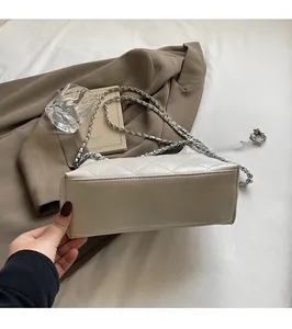 Detailansicht der beigen gesteppten Beuteltasche mit dickem Boden und Kettenriemen