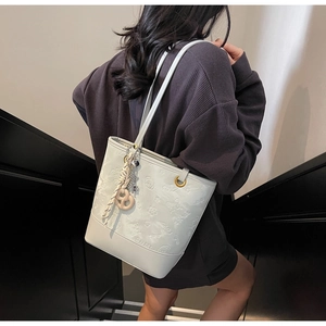 Dettaglio della borsa tote color crema con goffratura floreale e scritte SNML incise