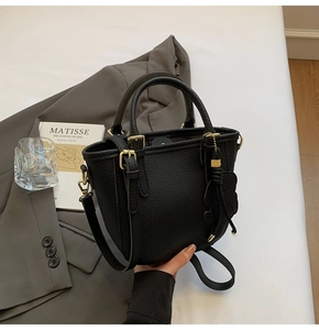 Detail of black lychee grain leather bucket bag with top handles and adjustable strap