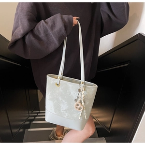 Dettaglio della borsa tote color menta con motivi cartoon a rilievo e ciondolo intrecciato