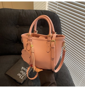 Detail of pink lychee leather bucket bag with gold hardware and bear charm